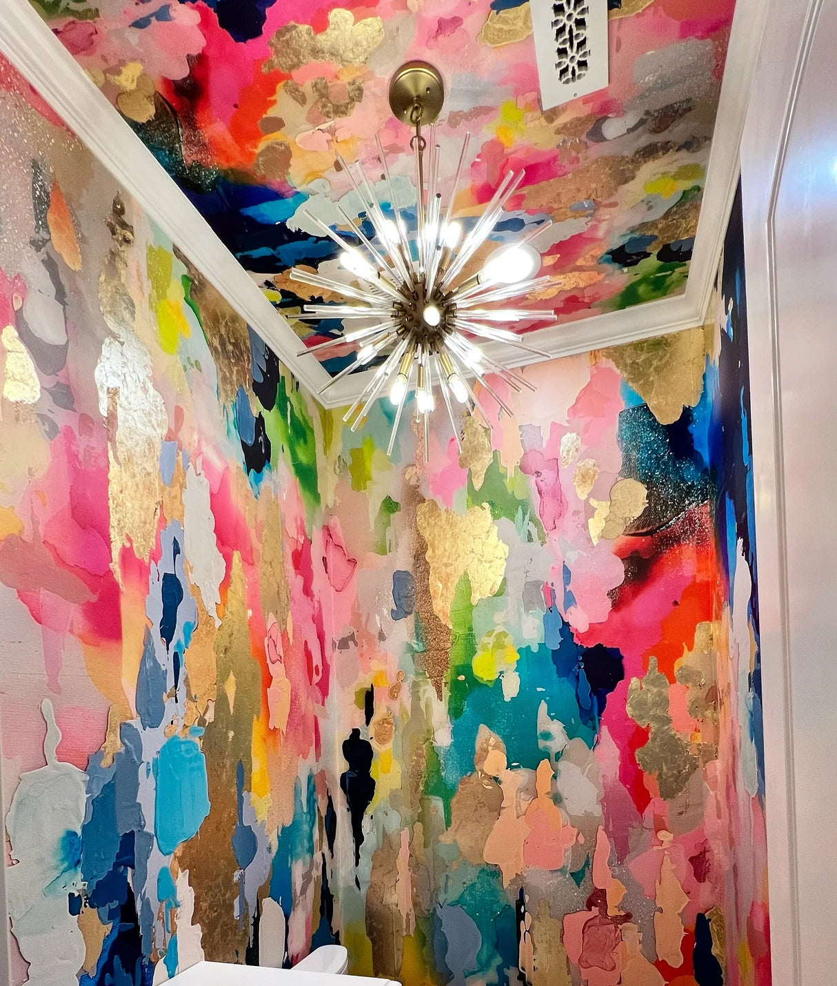 This photo shows the installation of the large abstract wallpaper design. The bathroom wall decor features pinks, blues and turquoise colors with real gold leaf application.