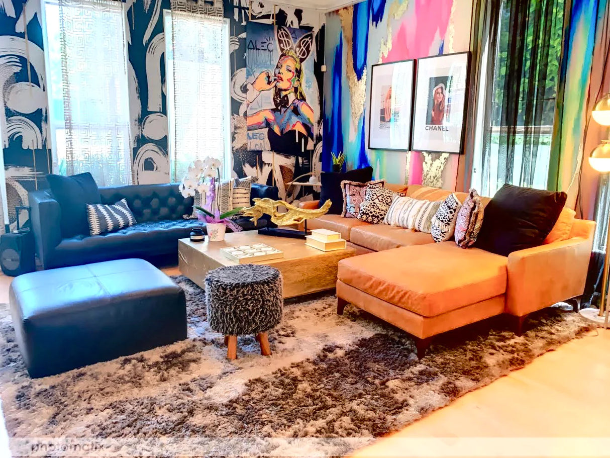 Best maximalist interior design concepts. This maximalist room features the colorful wallpaper with fuchsia, mints, blues, greens and golds. Luxury leather sectional couches, multi colored pillows and pop culture decor throughout the room.