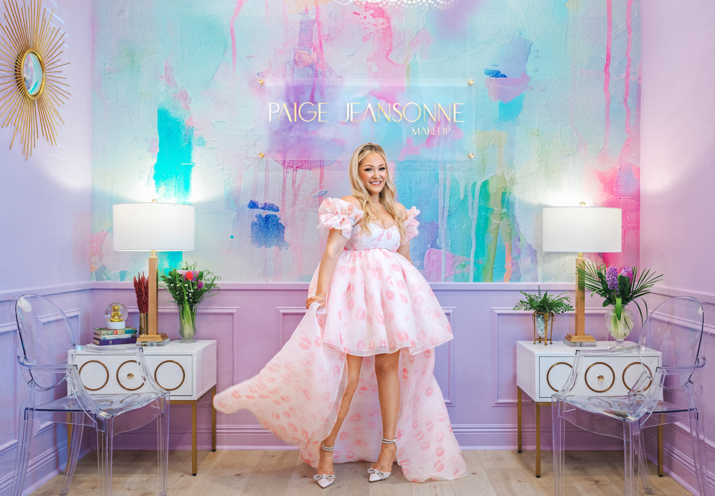 Woman in a pink dress standing in a stylish room with colorful wall art and decor.