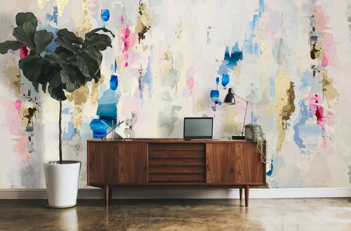 This tropical interior design image features a giant wallpaper mural with blues, pinks, grays and golds. The large potted trees and a wooden entry way table. This wallpaper design is perfect for waterfront properties, hotels, spas or salons that want to feature nautical elements.