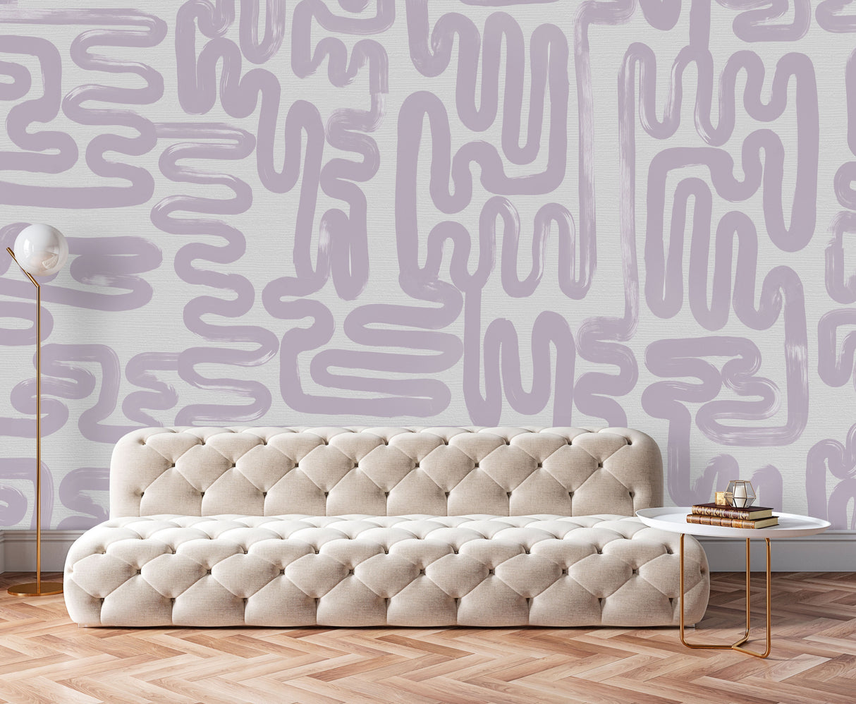 The refined abstract wallpaper design, Lavender Brushstrokes is the wall decor in this luxury living room space. The tufted furniture and copper coffee tables and lamp are great modern minimal features. Herringbone flooring provides a great counter balance interior design feature to this installation.