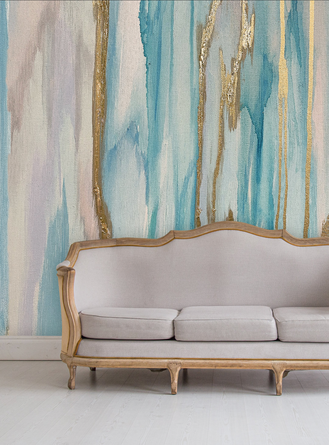 This close up living room decor was inspired by a classing camel back couch, light wood floors and this stunning large scale wallpaper mural. The wallpaper design features cool aquas, light lavenders and pinks and gold leafing.