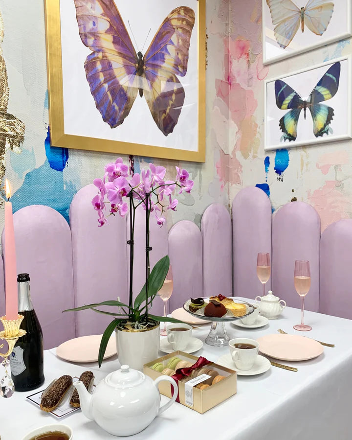 An elegant breakfast space in a coastal cafe featuring a large, abstract wallpaper mural, pastries and champagne.