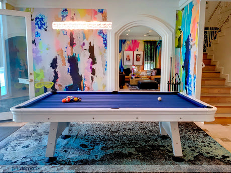 Colorful airbnb game room with large blue pool table, large area rug and a bright abstract wallpaper mural from Vivian Ferne.