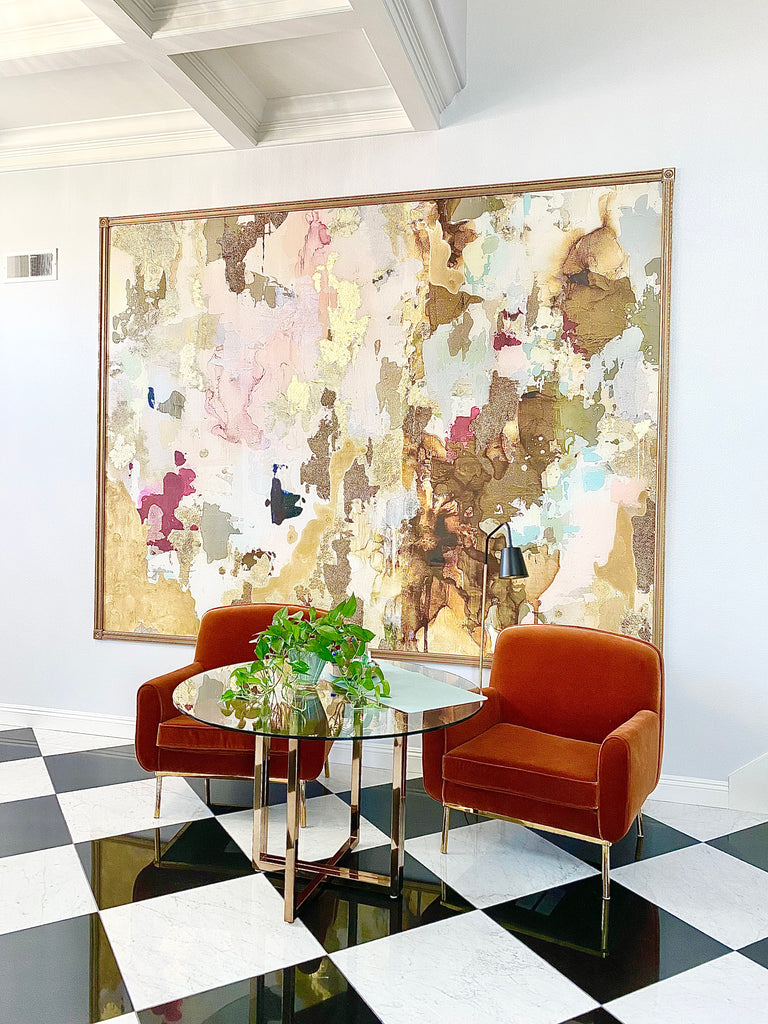 Luxury entry way decor with velvet arm chairs, marble flooring and large framed abstract wallpaper mural.