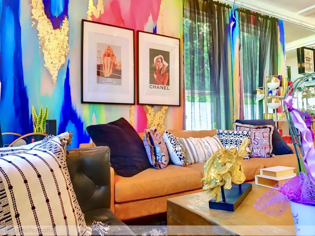 Best multi colored wallpaper design featured with pop culture artwork by Chanel. Luxury sectional couches and pillows, coffee tables and floral arrangements surround the maximalist wallpaper design. 