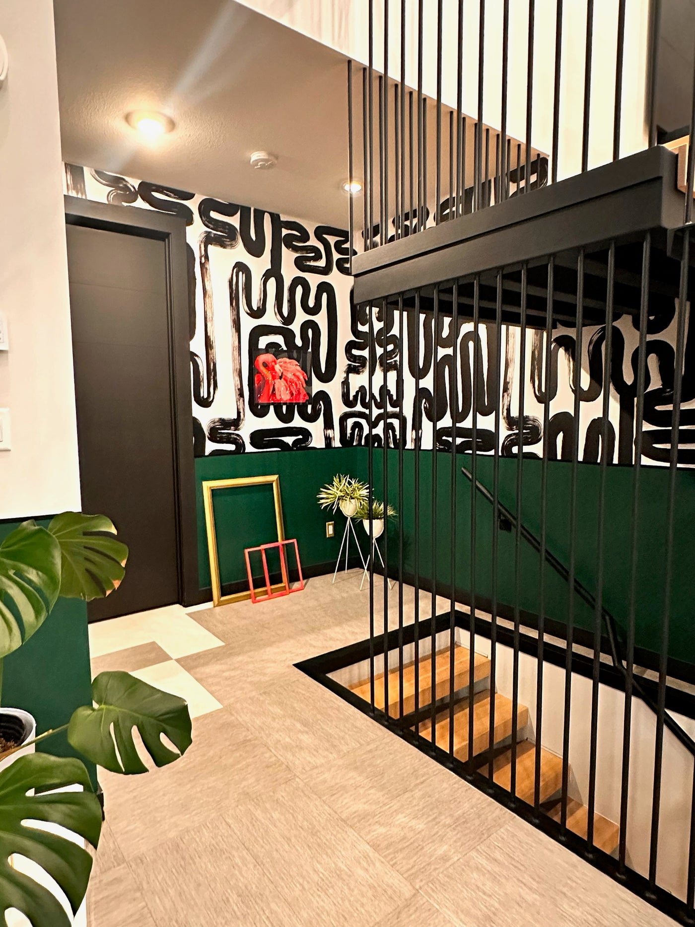Modern interior with a staircase, decorative wall with "Black Brustroke" wall paper, and plants. 