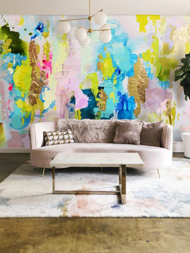 This living room decor pops with a burst of color from the chartreuse, lime and aqua abstract wallpaper design from women owned design shop, Vivian Ferne. The soft curved back sofa, pastel area rug and stone table delicately pull colors from the wallpaper to create a stunning combination between the wall art and the furniture. This wallpaper design includes real gold leafing for added texture and complexity.  