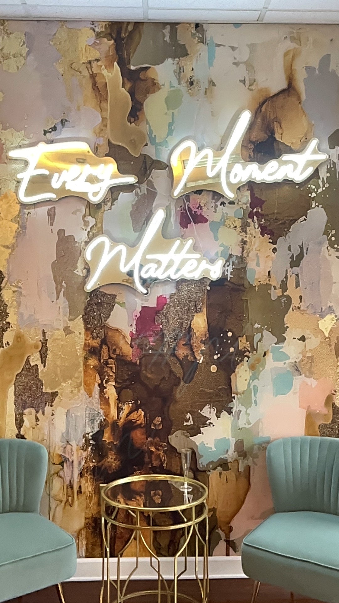 Caramel notes of the Cappuccino abstract wall mural with 'Every Moment Matters' neon light in a room setting. 
