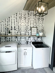 Accent walls can make any room pop. This laundry room accent wall features a monochromatic, large pattern wallpaper from famous interior designer, Vivian Ferne. This design is subtle yet engaging and provides just the right amount of energy to any interior design space.