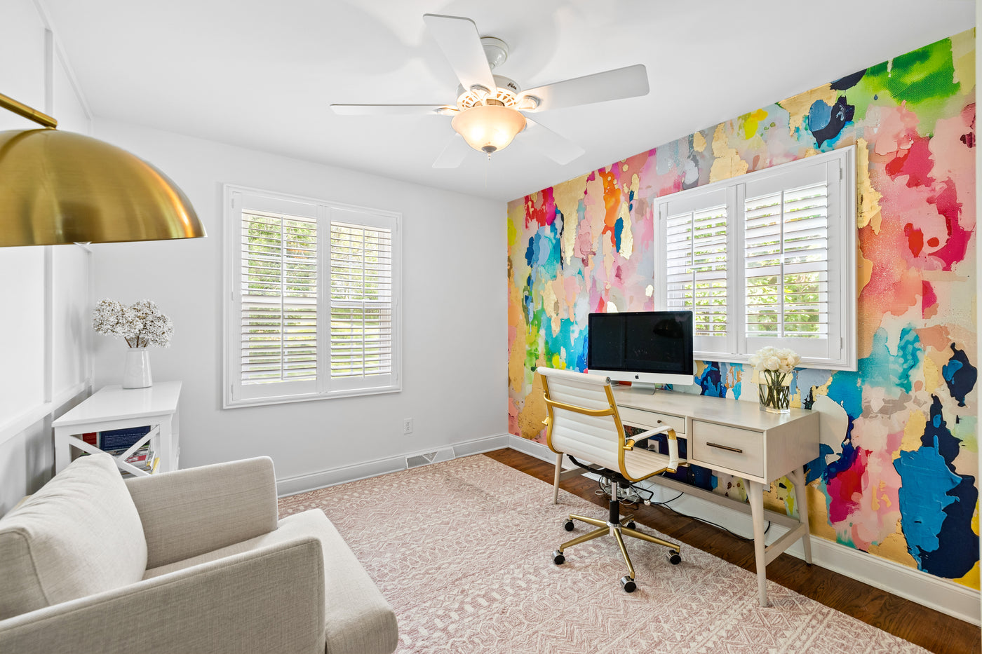 Home office with colorful gilded wall paper, desk, and chair.