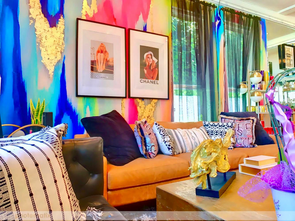 Best multi colored wallpaper design featured with pop culture artwork by Chanel. Luxury sectional couches and pillows, coffee tables and floral arrangements surround the maximalist wallpaper design. 