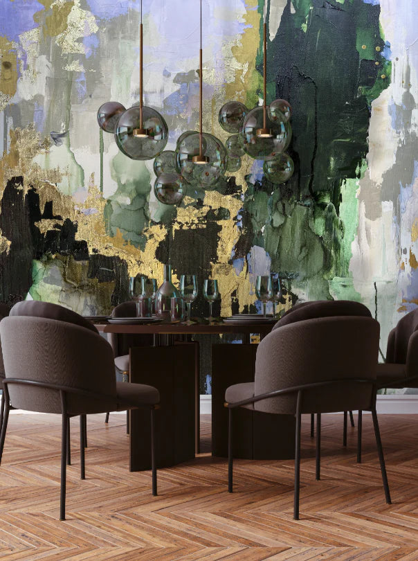 This staged dining room features modern decor and the abstract wallpaper design with green (kelly and emerald) gold, blue and grey. The design is inspired by the famous abstract artist Fran Maass who created the original image with acrylic paint and alcohol inks. The dining room features brown chairs, glass and wood tables, stemmed wine glasses and glass overhead lighting. The herringbone flooring creates a perfect foreground for this design concept.