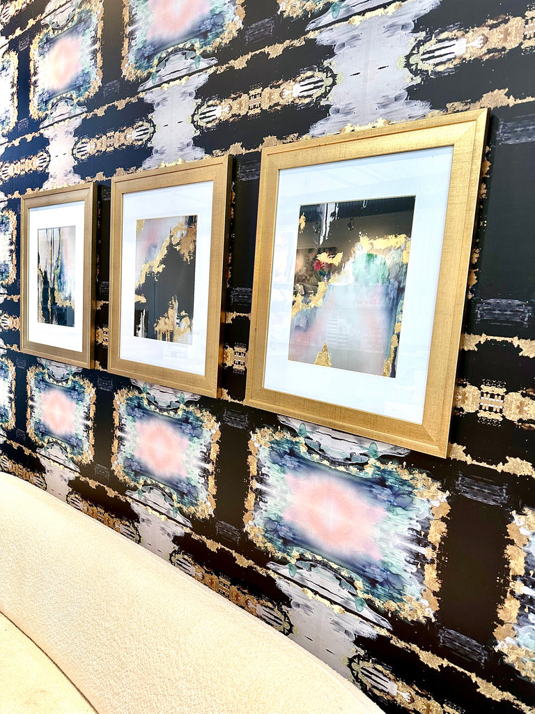 Brushed gold framed prints with abstract painting prints. The wall in this photo features large pattern wallpaper and gold framed prints.