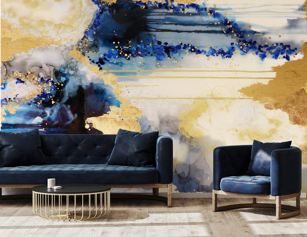 Blue and gold abstract accent wall. This abstract wallpaper design was inspired by the colors, tones and textures of the ocean. The mural sits behind luxury rustic blue suede furniture and black and gold coffee table. Distressed wood flooring allows the richly textured acrylic and alcohol ink design to shine through.
