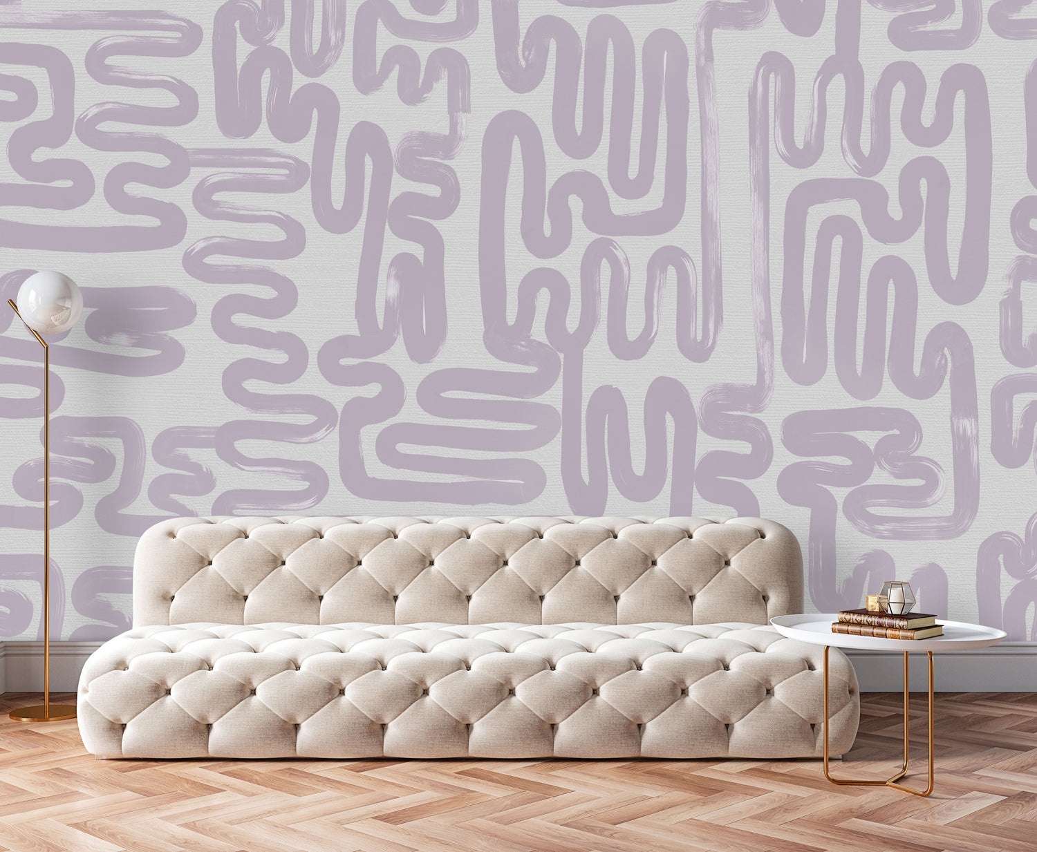 The refined abstract wallpaper design, Lavender Brushstrokes is the wall decor in this luxury living room space. The tufted furniture and copper coffee tables and lamp are great modern minimal features. Herringbone flooring provides a great counter balance interior design feature to this installation.