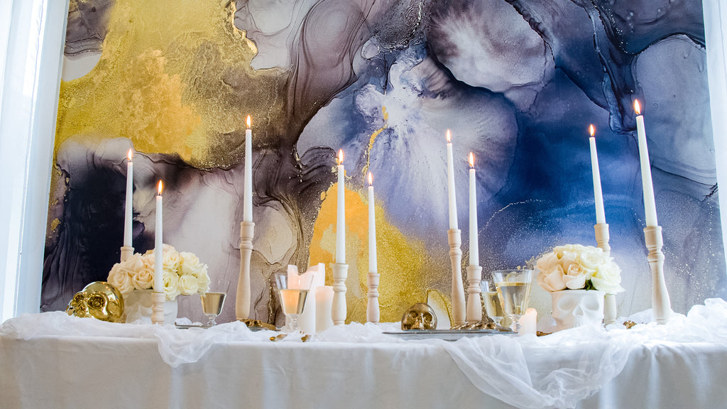 Interior Design photo shoot for luxury abstract gold, blue, and grey wallpaper. This installation was a part of Vivian Ferne's halloween decor photoshoot. The shoot included candles, white table decor, white rose flowers and gold skull decorations. 